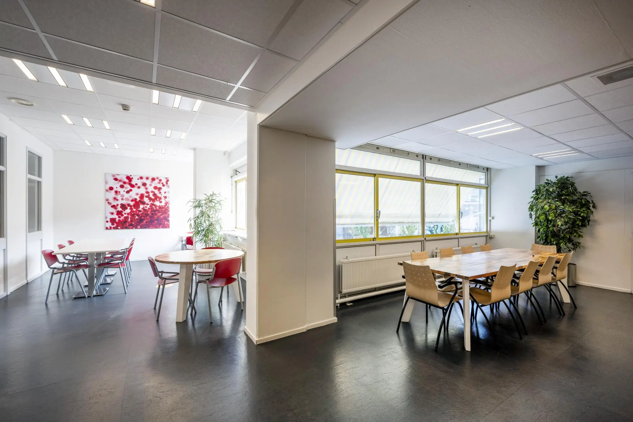 Moderne en lichte vergaderruimte aan de Jan Tooropstraat met meerdere tafels, stoelen en grote ramen met zonwering.